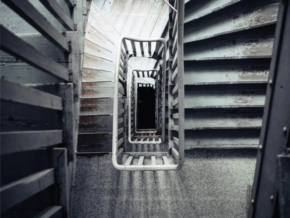 Cage d’escalier d’un immeuble vue d’en haut, volées de marches et rampe métallique